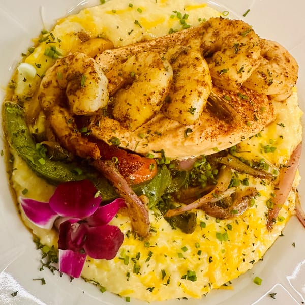 Snooks Grill's shrimp and grits with vegetables, garnished with a purple orchid.