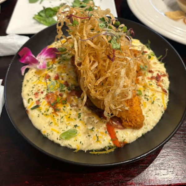 Snooks Grill & Cocktails' shrimp and grits, topped with crispy fried onions and a purple orchid.