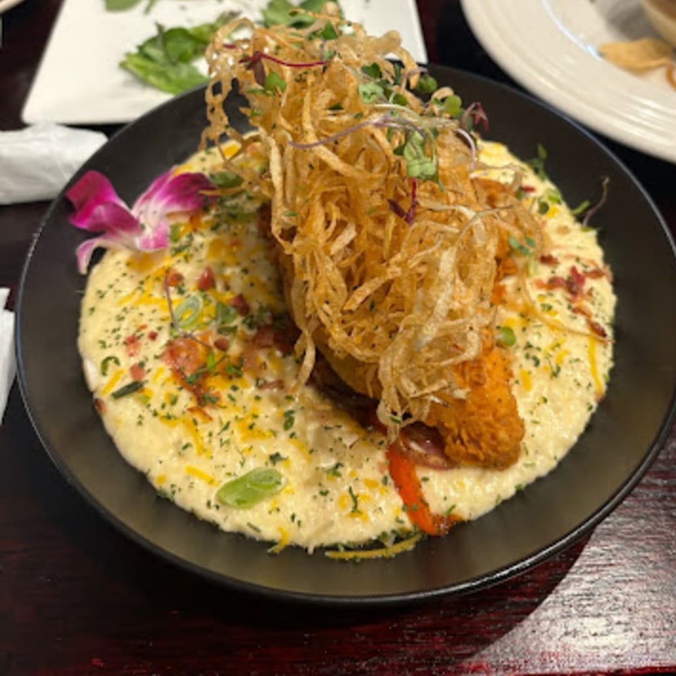 Snooks Grill & Cocktails' shrimp and grits, topped with crispy fried onions and a purple orchid.