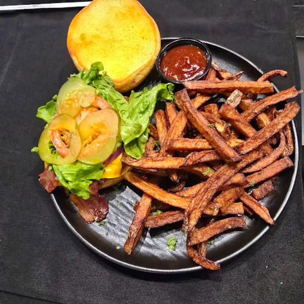 Snooks Grill & Cocktails' burger with bacon, lettuce, pickles, and a side of fries and ketchup.