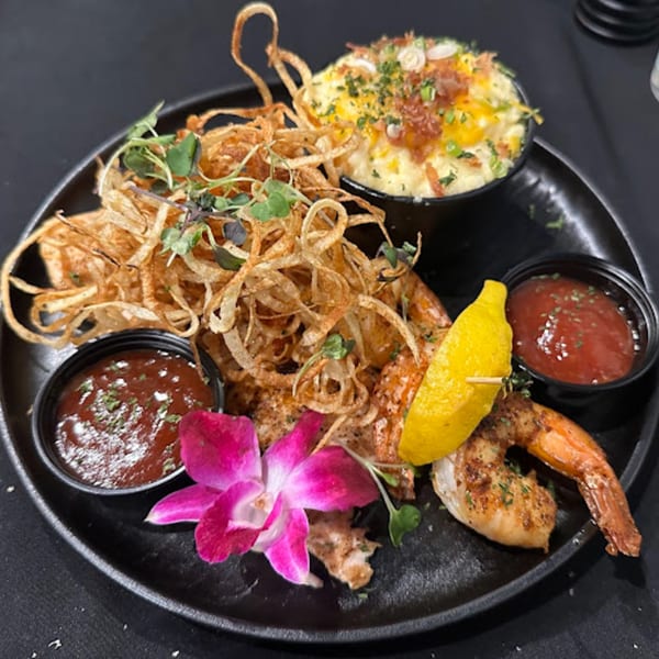 Snooks Grill & Cocktails' American dish with shrimp, crispy onions, macaroni and cheese, and sauces.