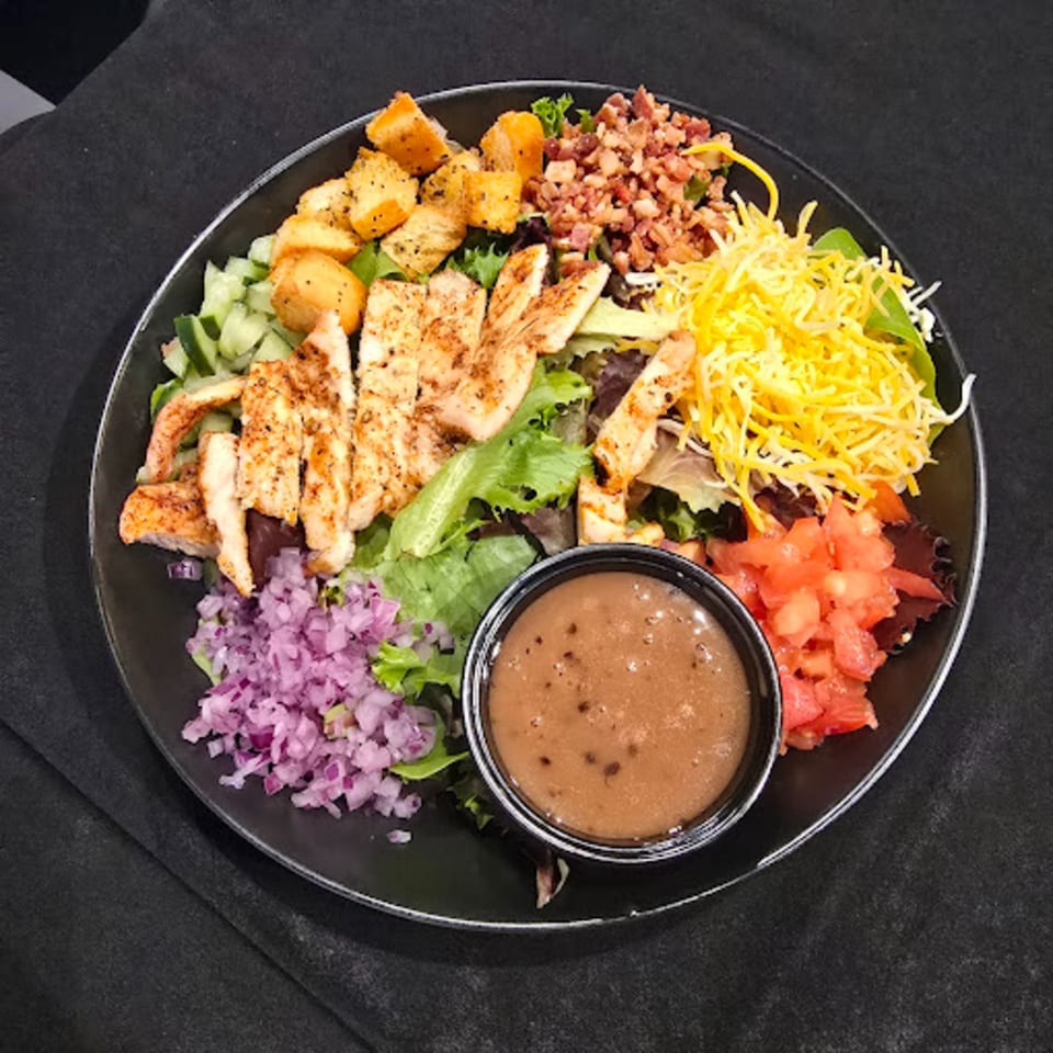 Snooks Grill & Cocktails' grilled chicken salad with bacon, cheese, croutons, and dressing.