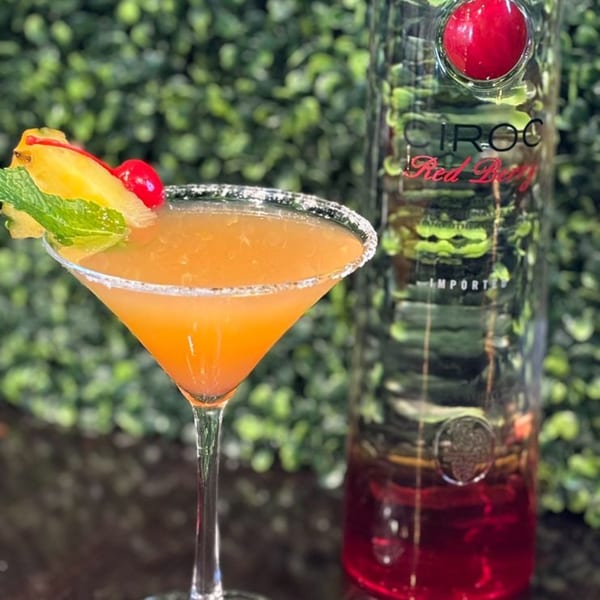A Snooks Grill & Cocktails martini with pineapple, cherry, and mint, next to a Ciroc Red Berry bottle.