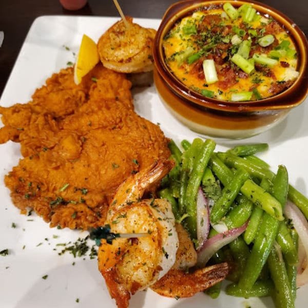 Fried chicken, grilled shrimp, green beans, and a bowl of cheesy grits with bacon and scallions.