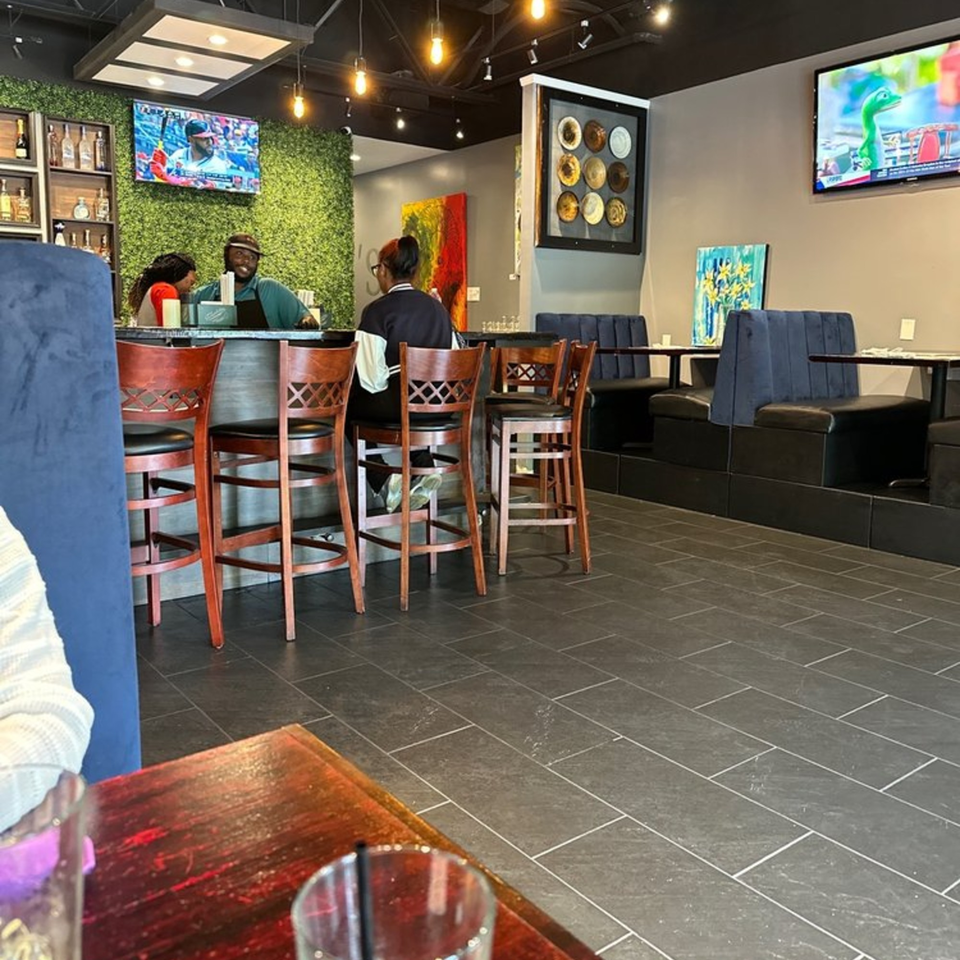 Interior of Snooks Grill & Cocktails with patrons at the bar, booth seating, and TVs on the walls.